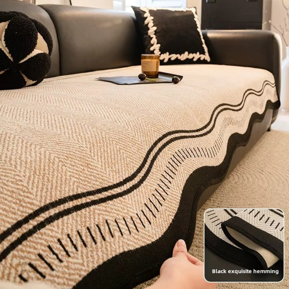 Hand lifting the black bound edge of the beige seat cover with a close inset of the hem