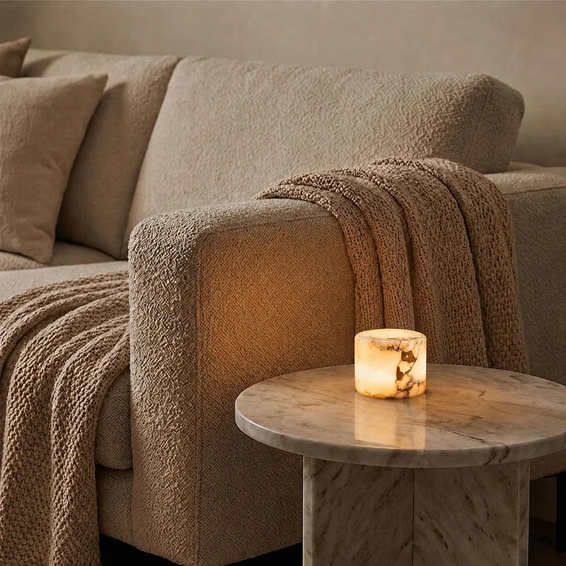Ystad lamp glowing on a marble side table beside a sofa