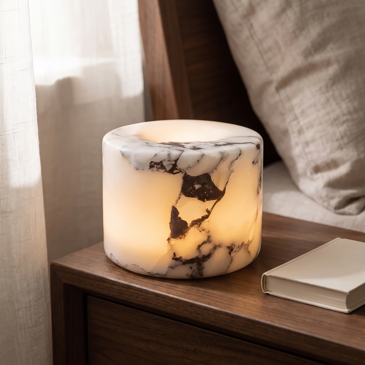 Ystad marble lamp in Ivory Noir glowing on a walnut nightstand